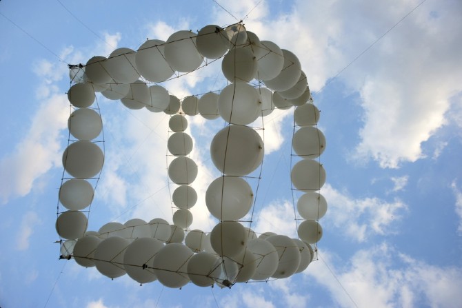 Balloon cube installation seen from below against clouds