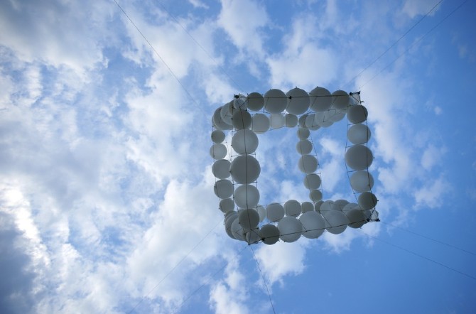 Balloon cube drifting high in an open sky